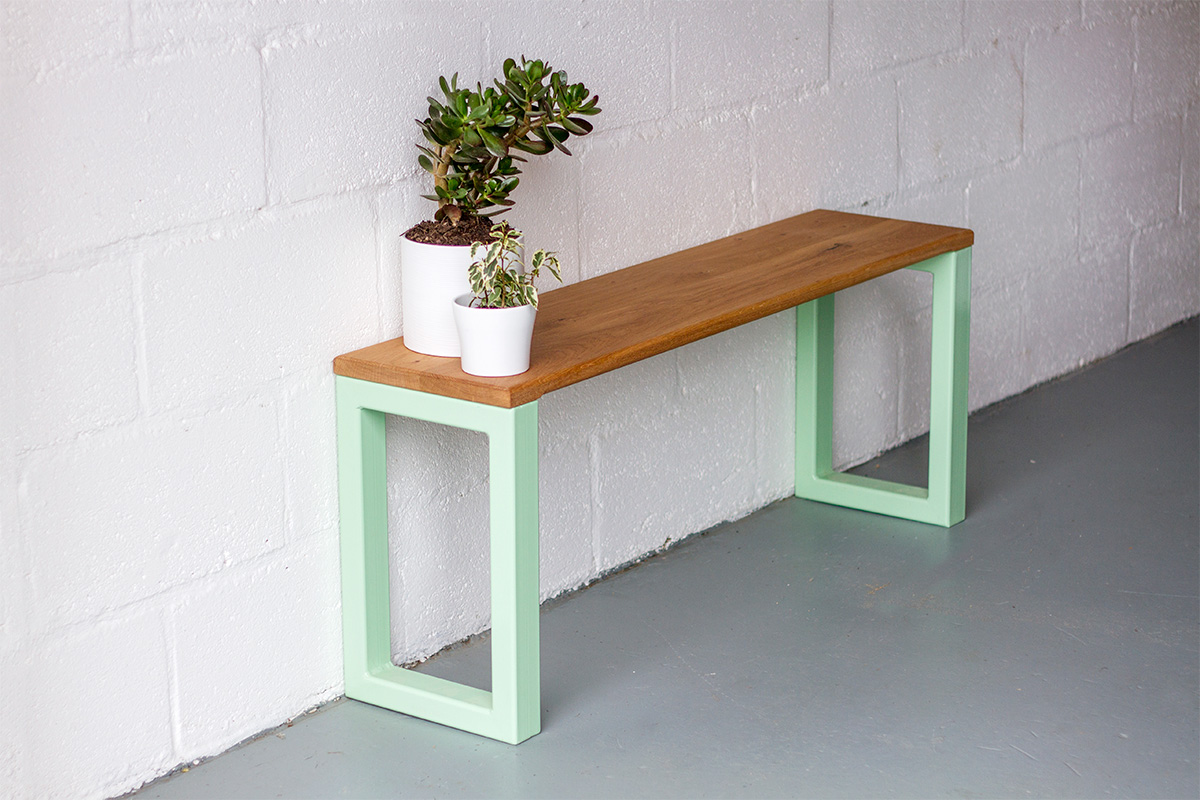 nola bench in pistachio coloured steel and oak bench seat, with pot plants at one end