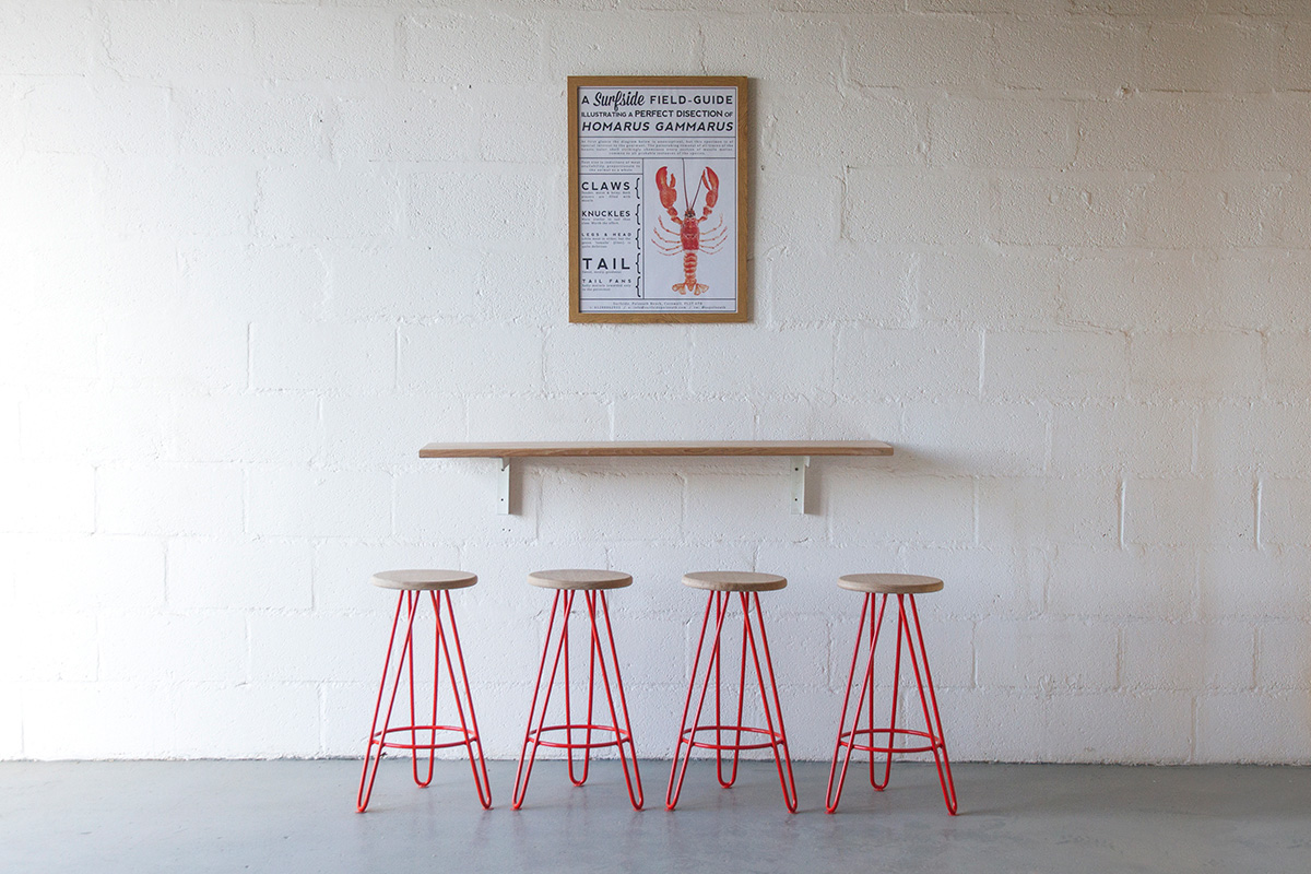 red legged barstools underneath a wall mounted shelf and lobster poster