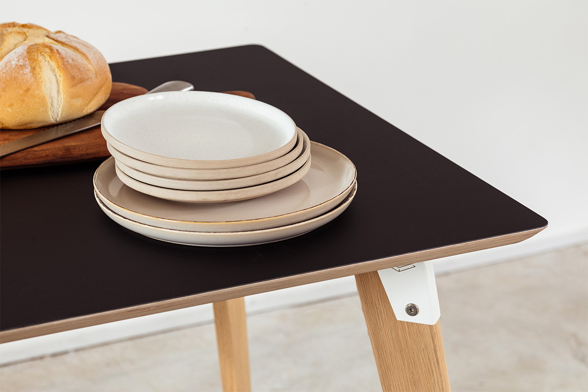 corner of a modpop dining set with black fenix table and bench tops, white brackets and oak legs